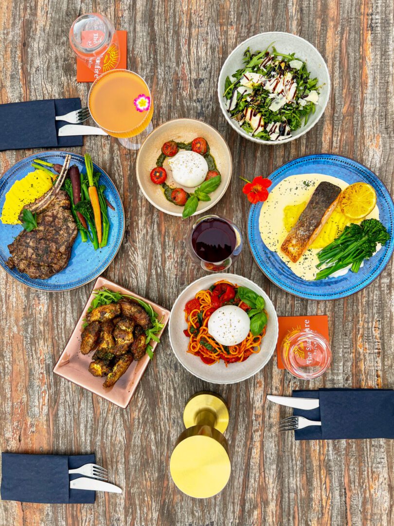 A colorful spread of various dishes and drinks on a wooden table.